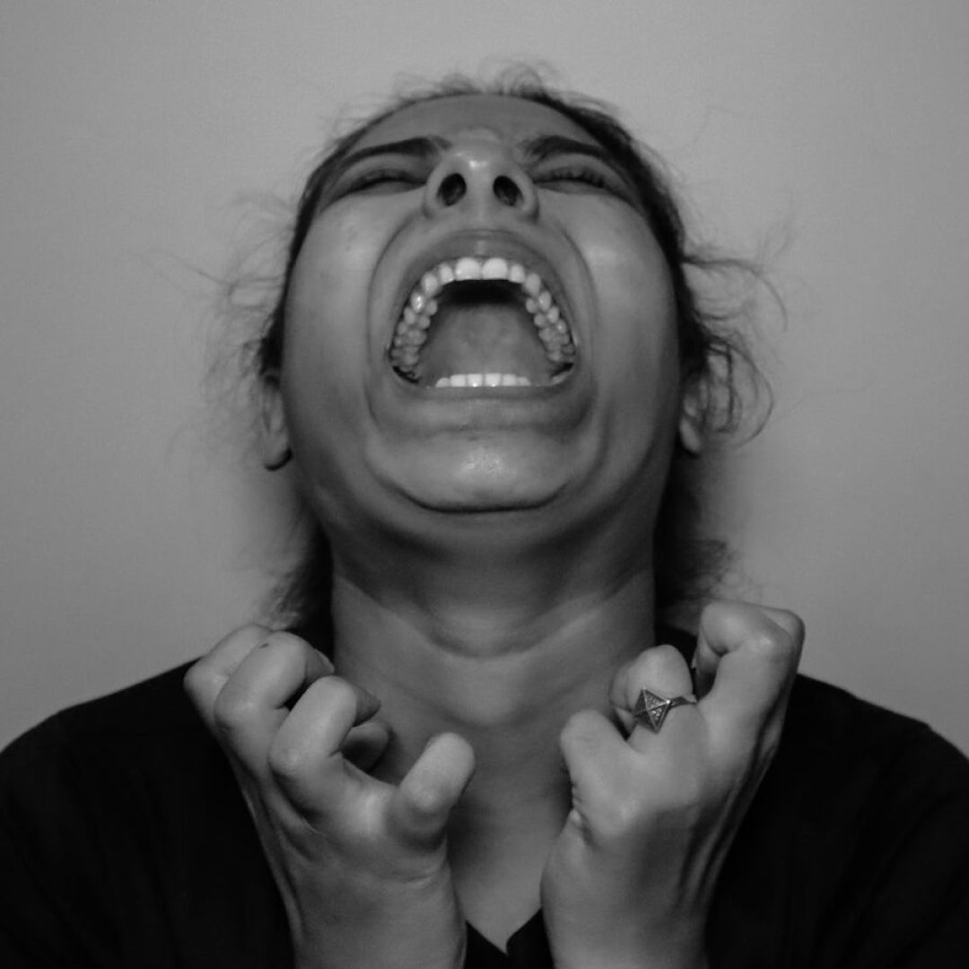 a woman with her mouth open and hands in front of her face